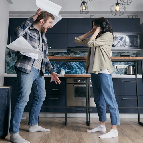 A man in a plaid shirt throws papers in a kitchen A-man-in-a-plaid-shirt-throws-papers-in-a-kitchen